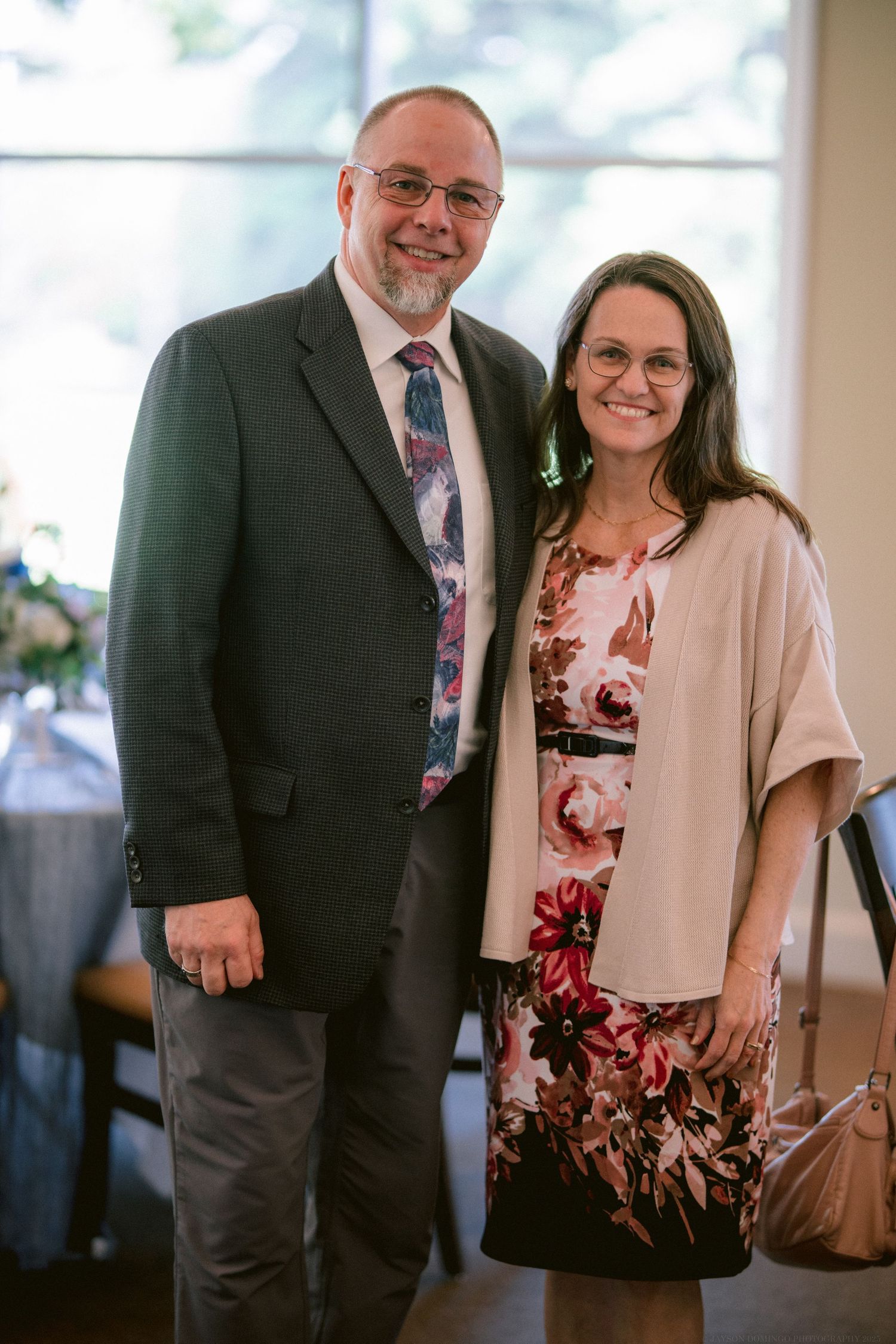 Couple smiling together at formal event wearing coordinated dressy attire.
