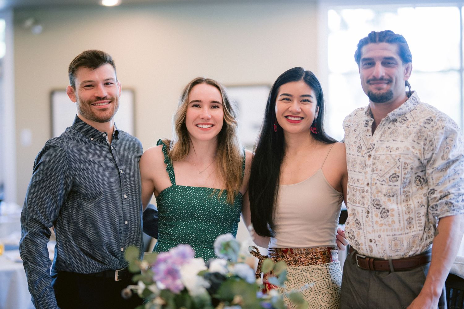 Two couples posing together at formal event with floral decorations.