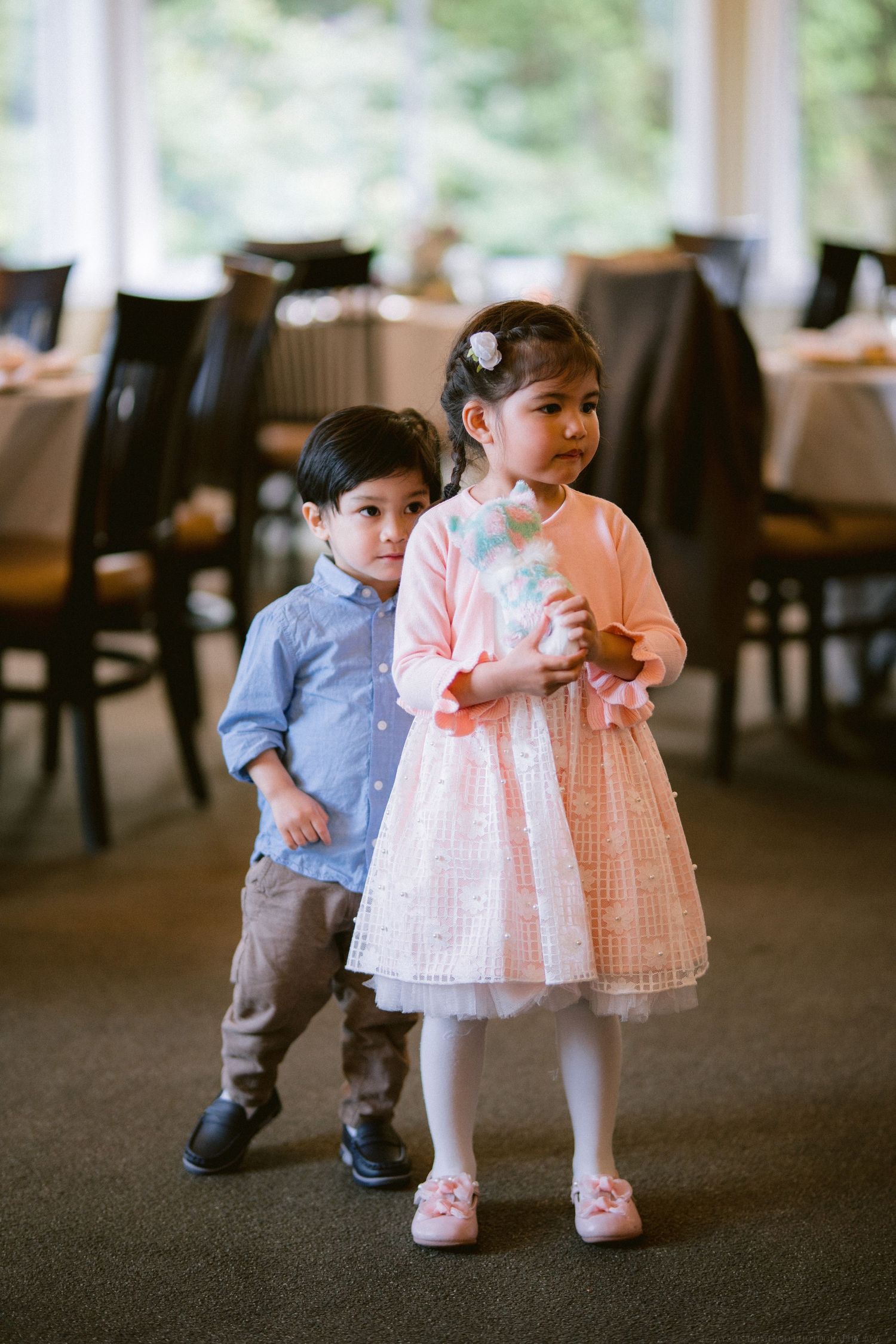 Two young children in formal attire standing together at special event.