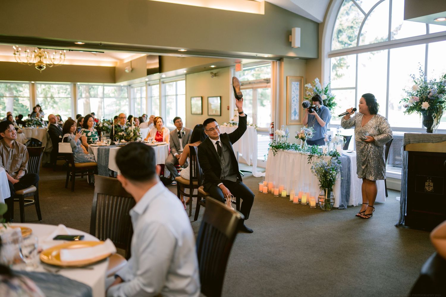 Wedding celebration in a bright reception hall with guests dancing and mingling.