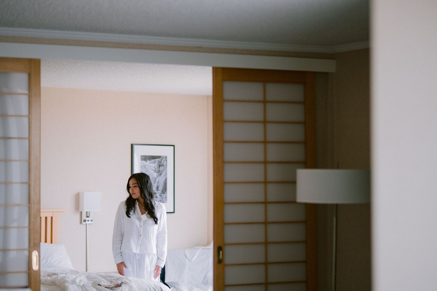 A person in white stands in a minimalist room with Japanese-style sliding doors.