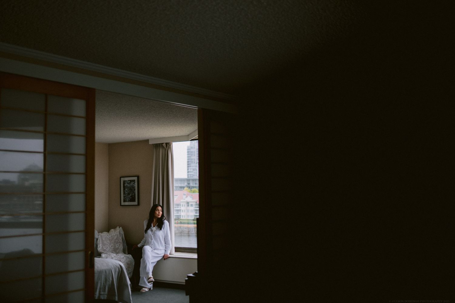 A silhouetted figure stands in a dimly lit doorway of a hotel room.