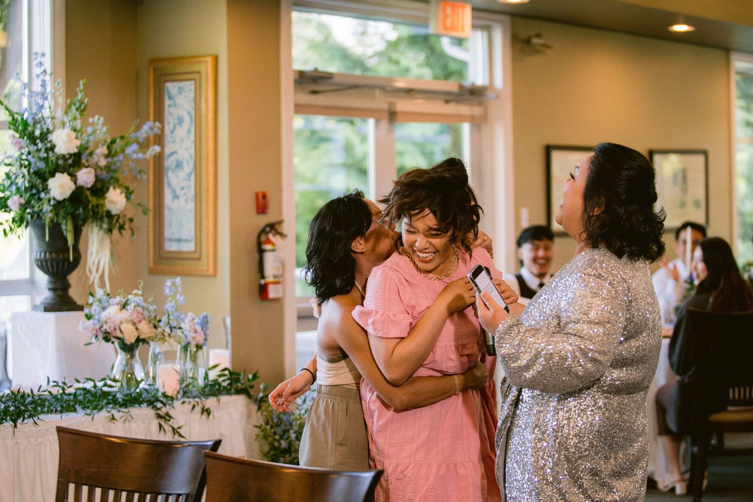 Guests celebrate at a wedding reception with floral decorations and warm lighting.