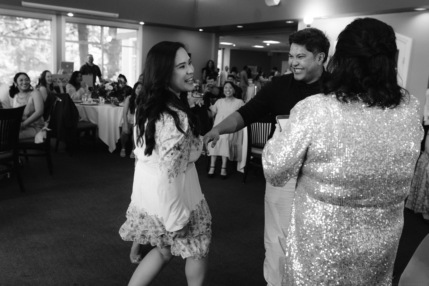 People dancing and celebrating at a wedding reception in a banquet hall.