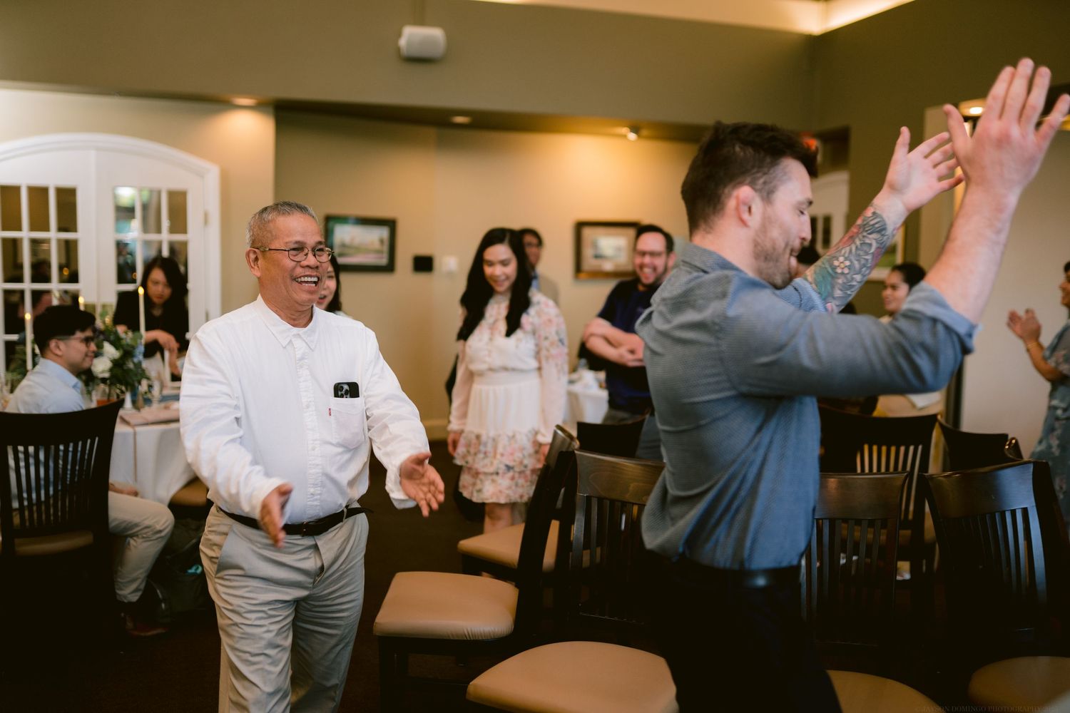 Guests and staff share a joyful moment during a celebration in an indoor dining room.