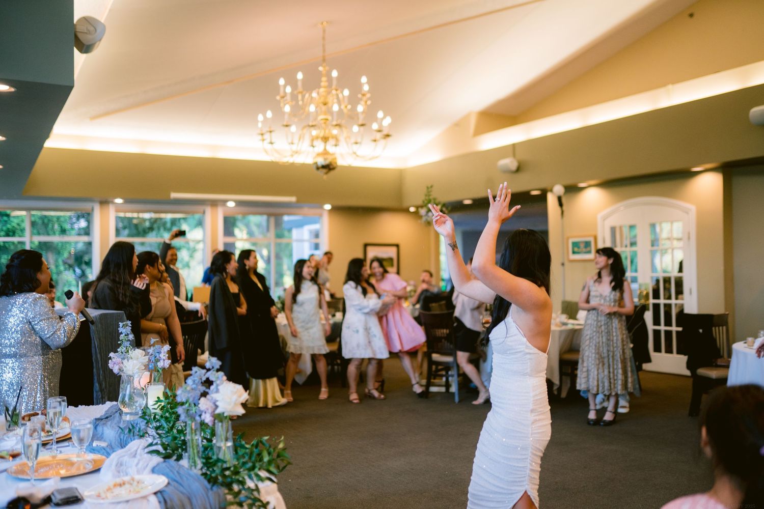 Celebration in full swing with guests dancing under elegant chandelier in reception venue.