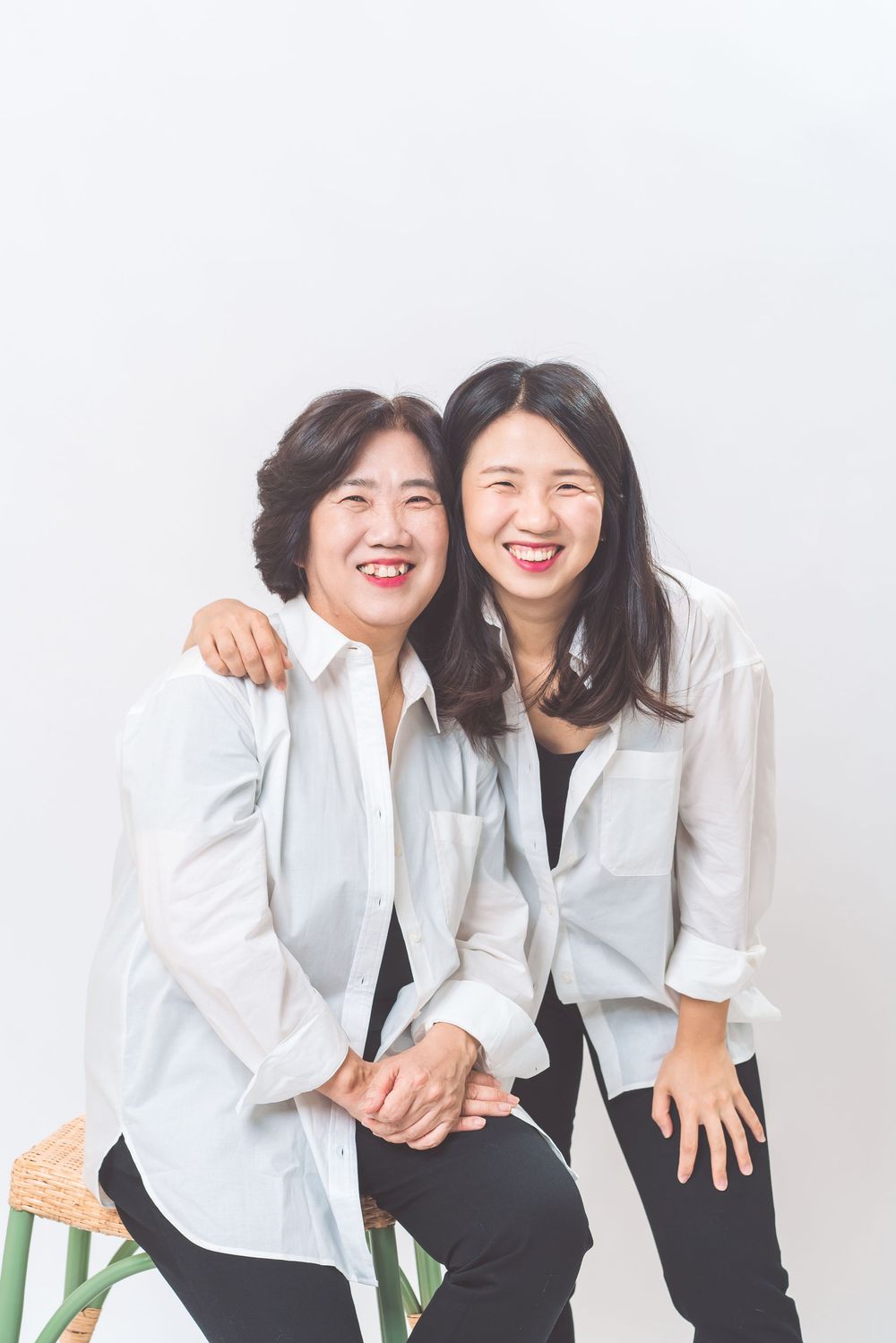 Two people in white button-down shirts sharing happy moment against light background.