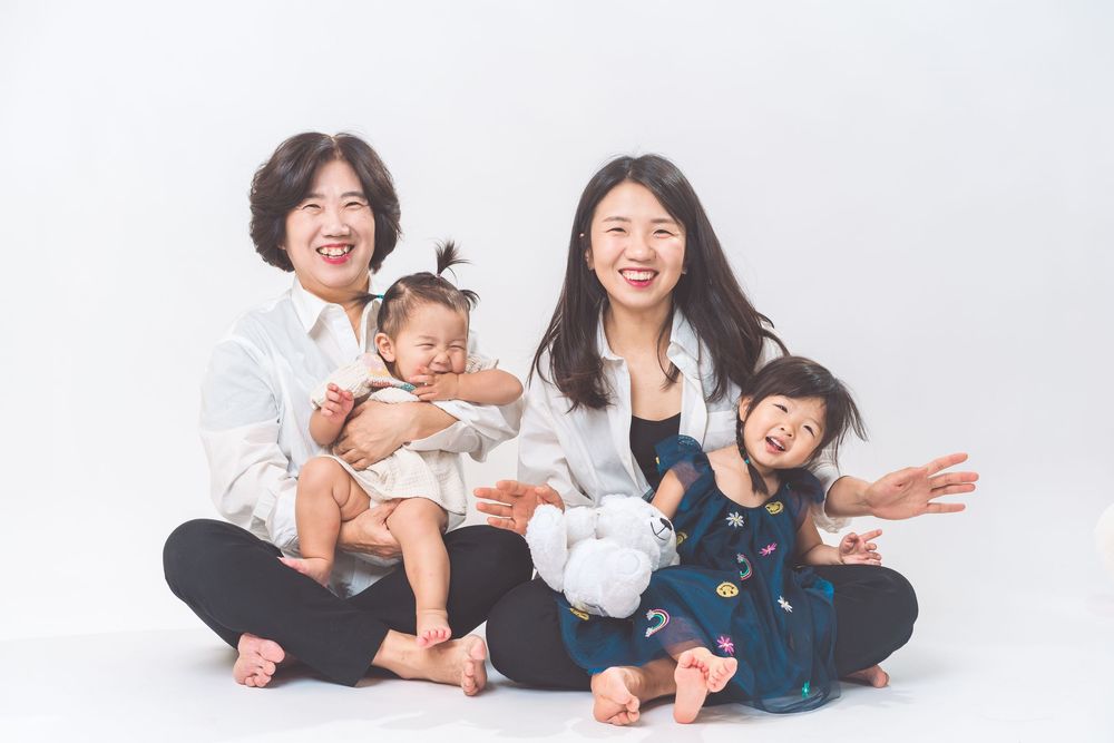 Playful family portrait with children on white background showing joyful expressions.