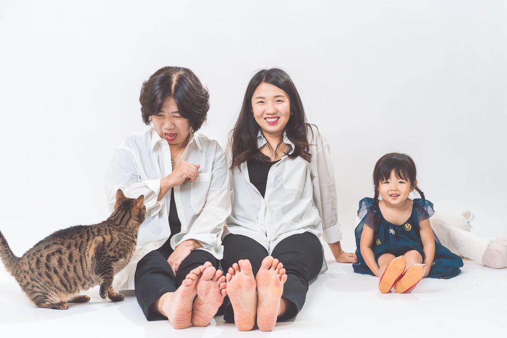 Family sitting on floor with cat, all wearing casual white shirts.