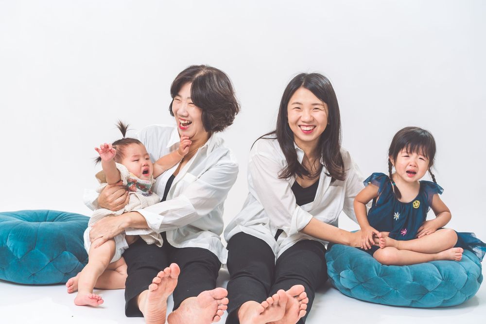 Family laughing together while sitting on floor with blue cushions.