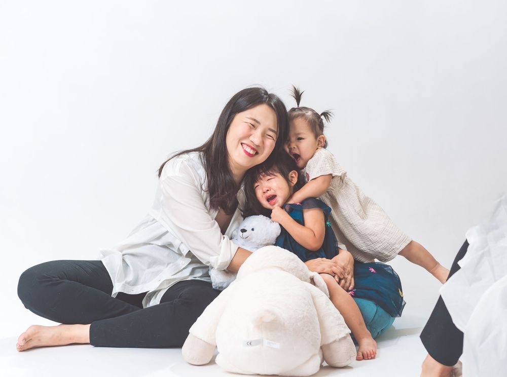 Candid family moment with parent and children playing on white floor.
