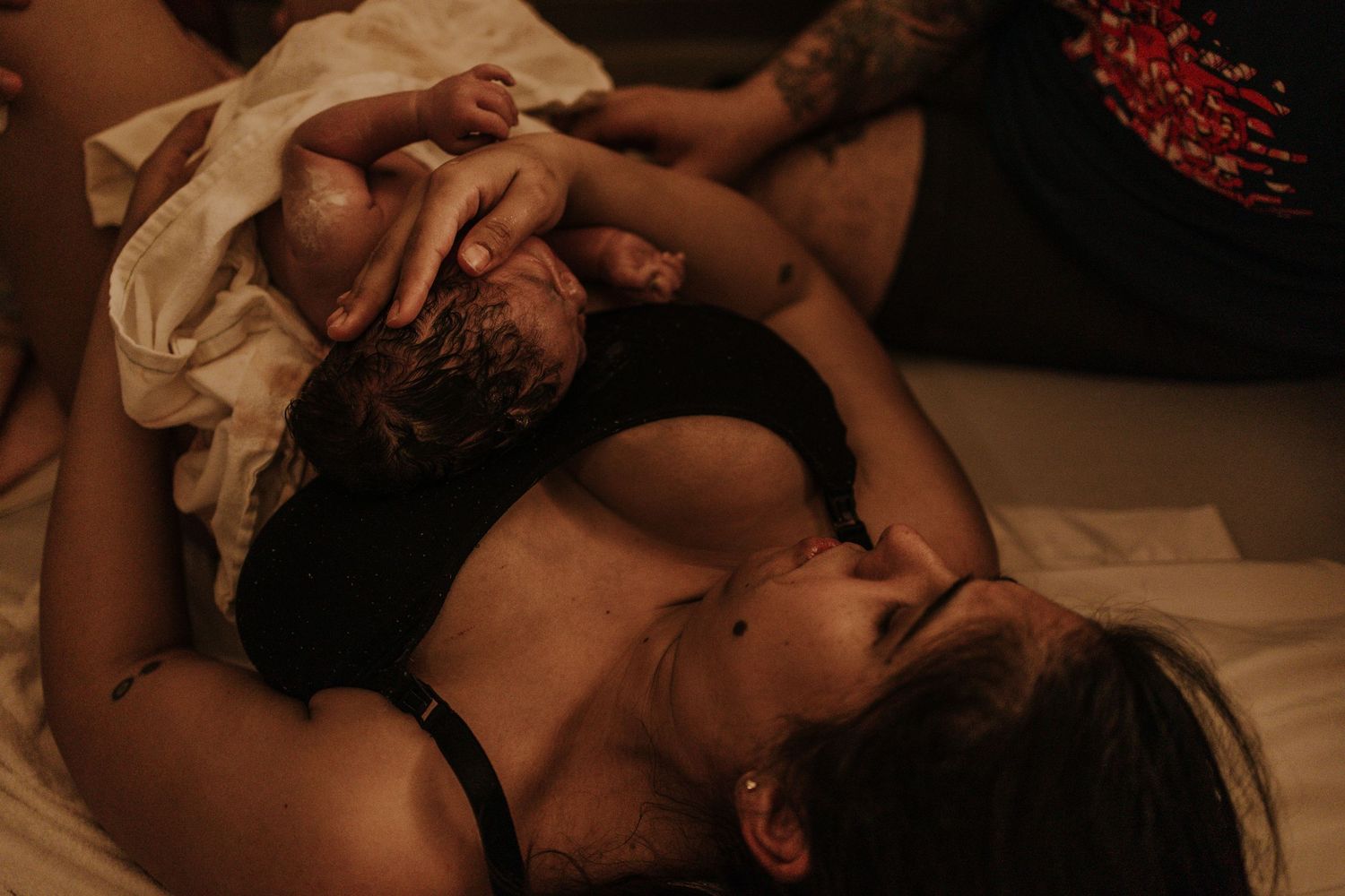 woman holding her newborn baby minutes after she gave birth, relieved.