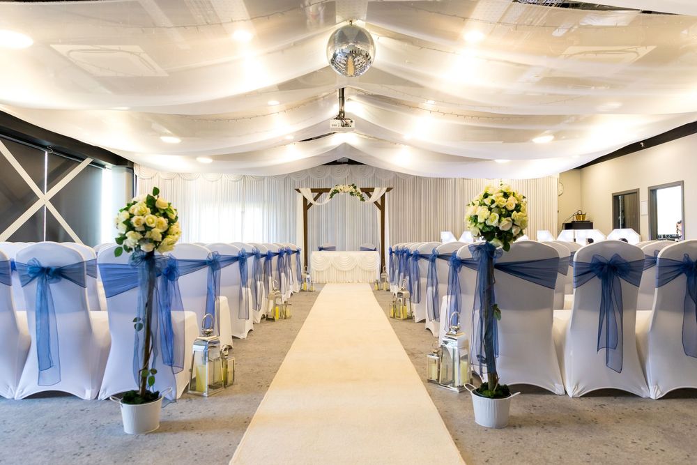Ceremony room with white chairs and blue sashes at the Village Hotel in Portsmouth, set for Emma and Daniel’s wedding.
