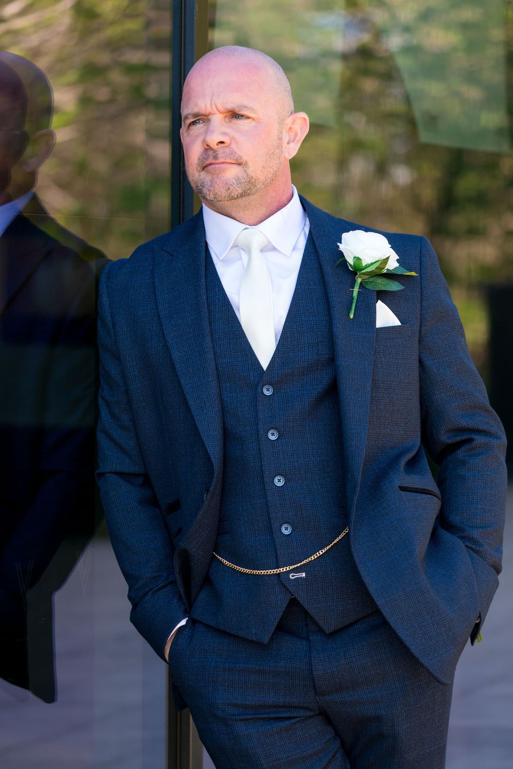 Groom Daniel standing outside in a navy suit and white rose buttonhole at the Village Hotel, Portsmouth.