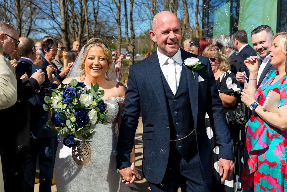 Bride and groom walking through guests blowing bubbles after the ceremony at the Village Hotel, Portsmouth.
