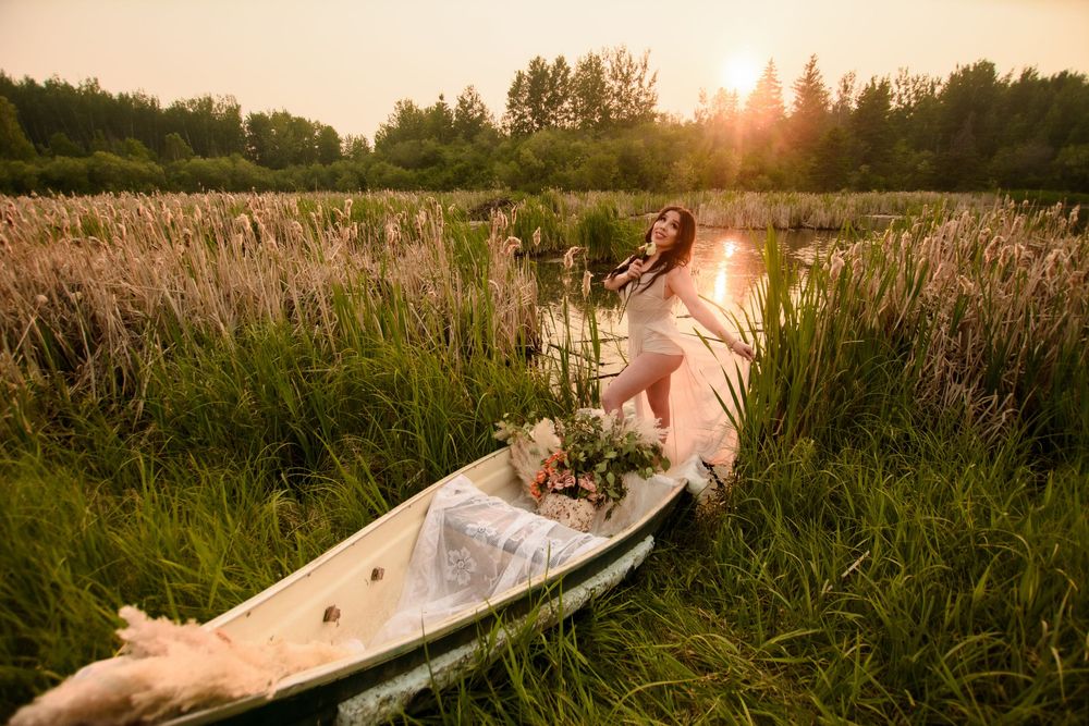Scenic view of a tall grass field at sunset with a light glow filtering through trees in the background.