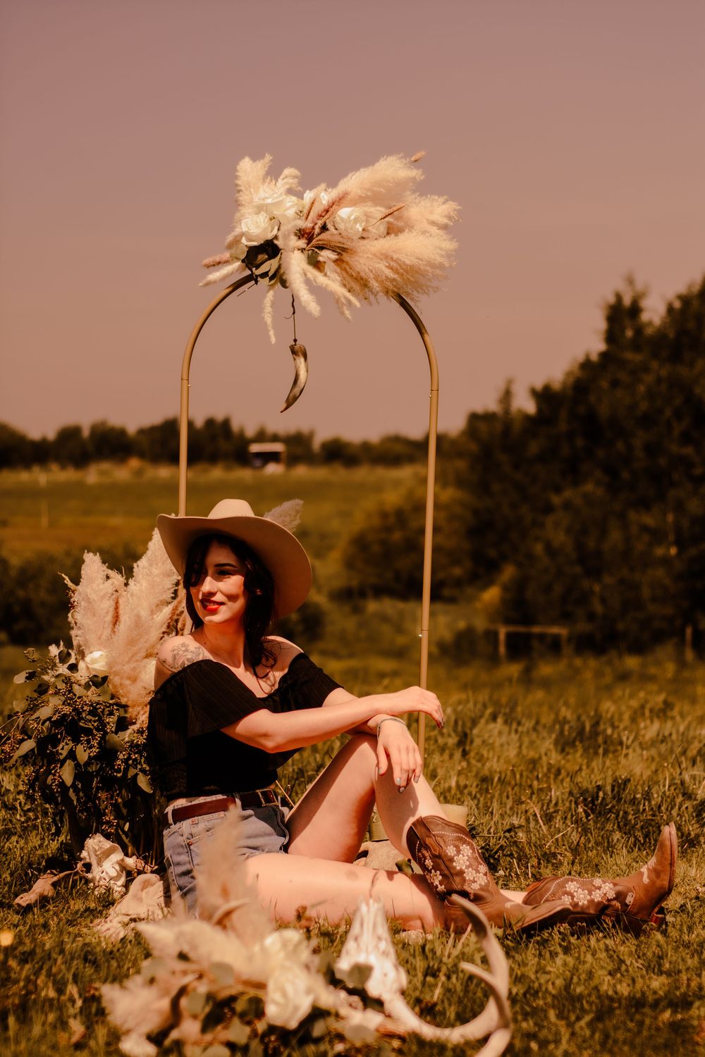 Stylish western-inspired photoshoot in a field with pampas grass decorations at golden hour.