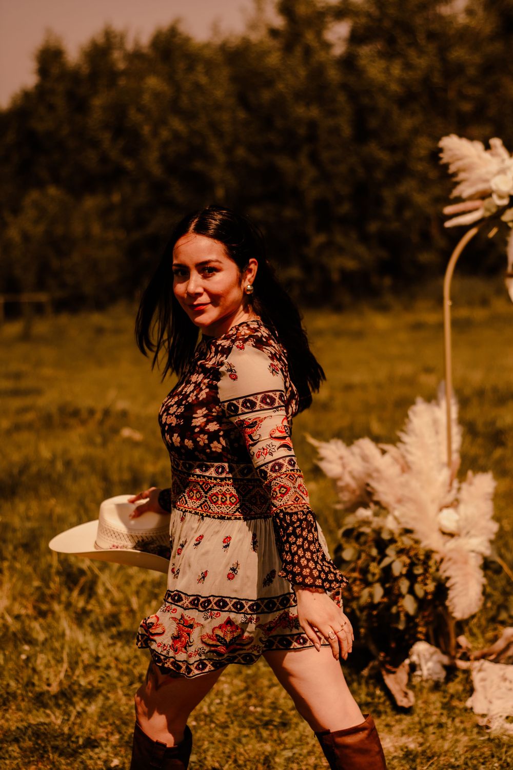Dancing figures in patterned dresses twirl through a sun-drenched meadow.