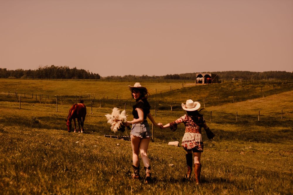 A wide shot of people walking through a rustic grassland landscape at dusk.