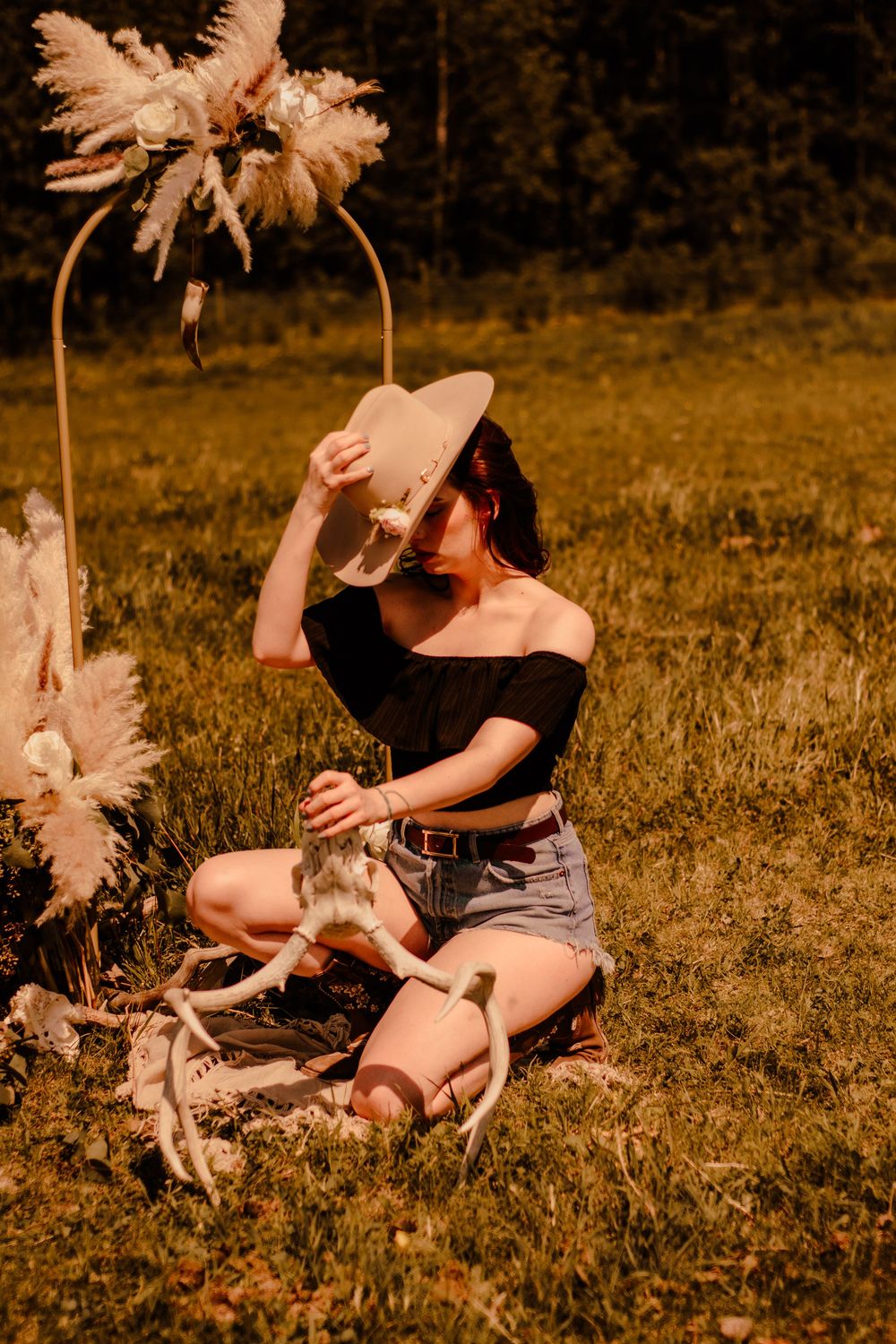 Dreamy outdoor photoshoot in a golden field with pampas grass decorations creating a boho aesthetic.