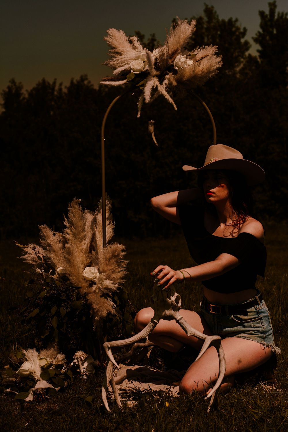 Moody sunset portrait with decorative pampas grass arch and western styling.