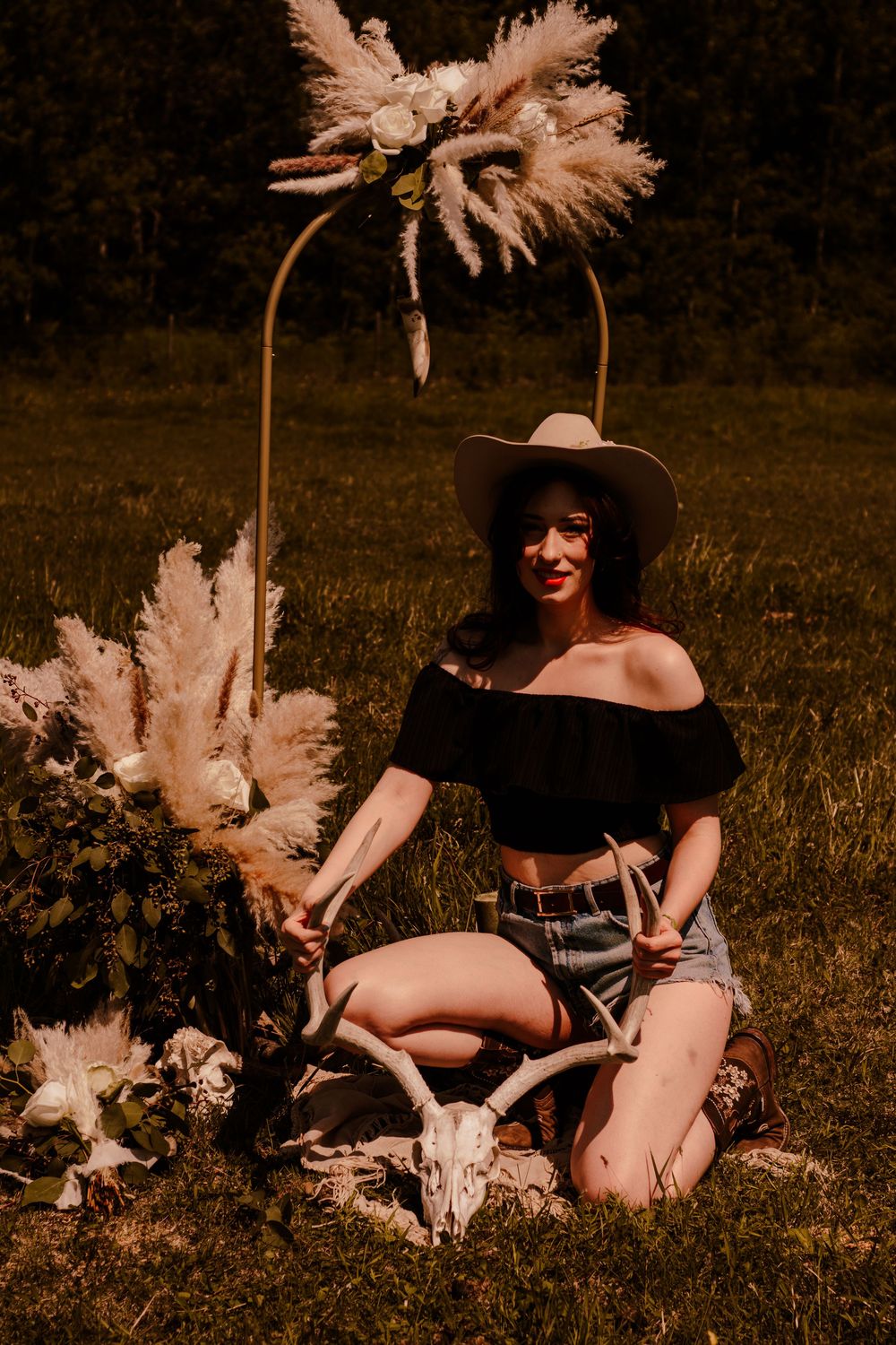 Outdoor portrait session with bohemian western styling and natural pampas grass decorations.