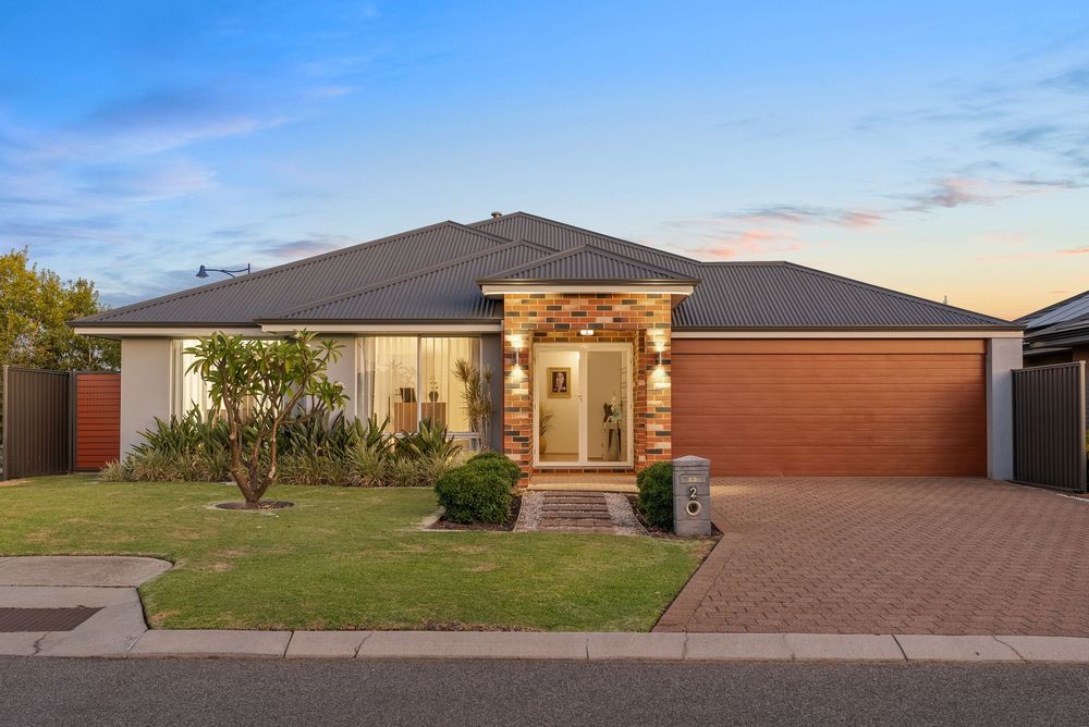 Modern single-story brick house with double garage and manicured lawn at sunset showcases contemporary suburban living.