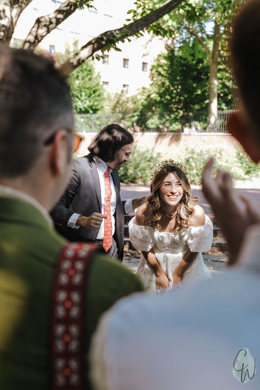 Joyful moment captured at an outdoor wedding celebration with guests in traditional attire beneath green trees.