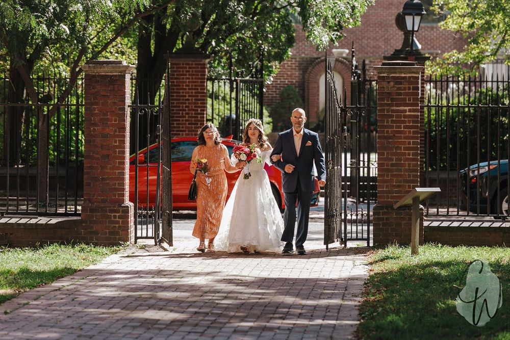 A scenic bridal party photoshoot along a brick pathway with lush greenery at an outdoor wedding venue.