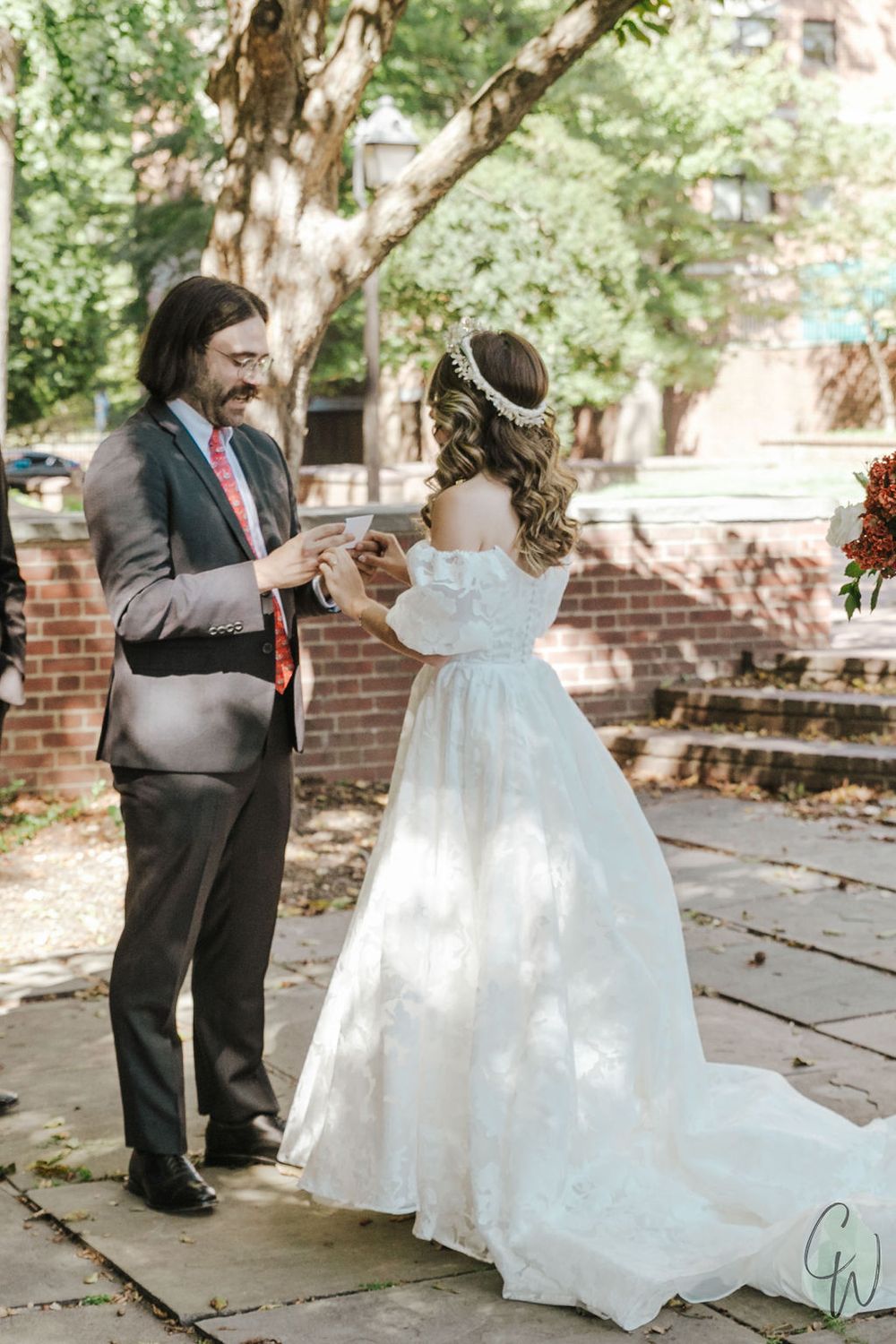 A couple shares a sweet first-look moment before their wedding on a brick-paved outdoor patio surrounded by greenery.
