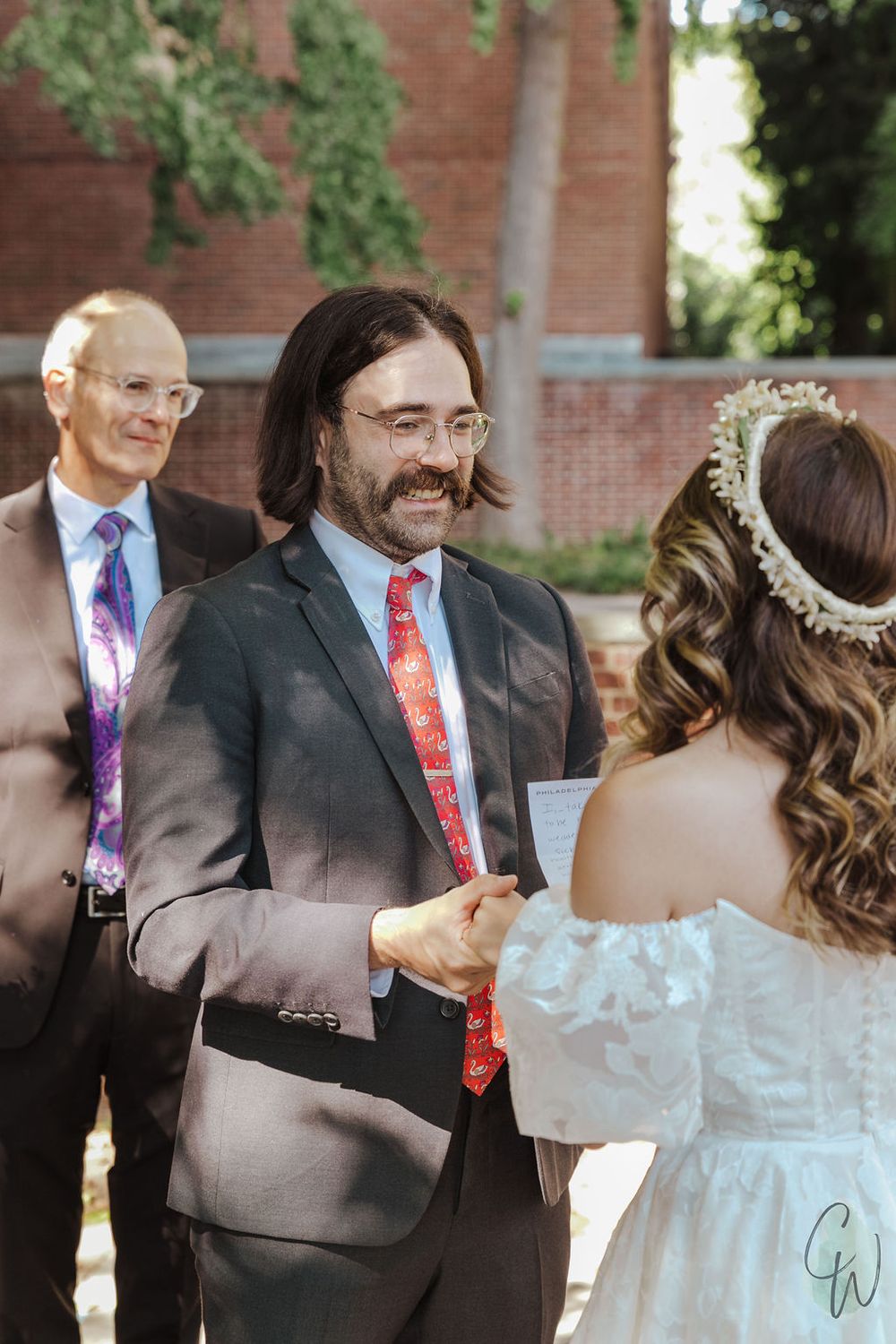 A first look sequence of newlyweds during their wedding day outside a brick building.
