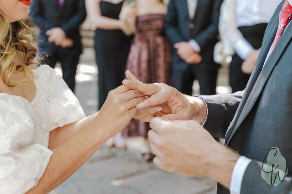 Close up view of two hands feeding each other slices of wedding cake in a traditional cake cutting gesture.