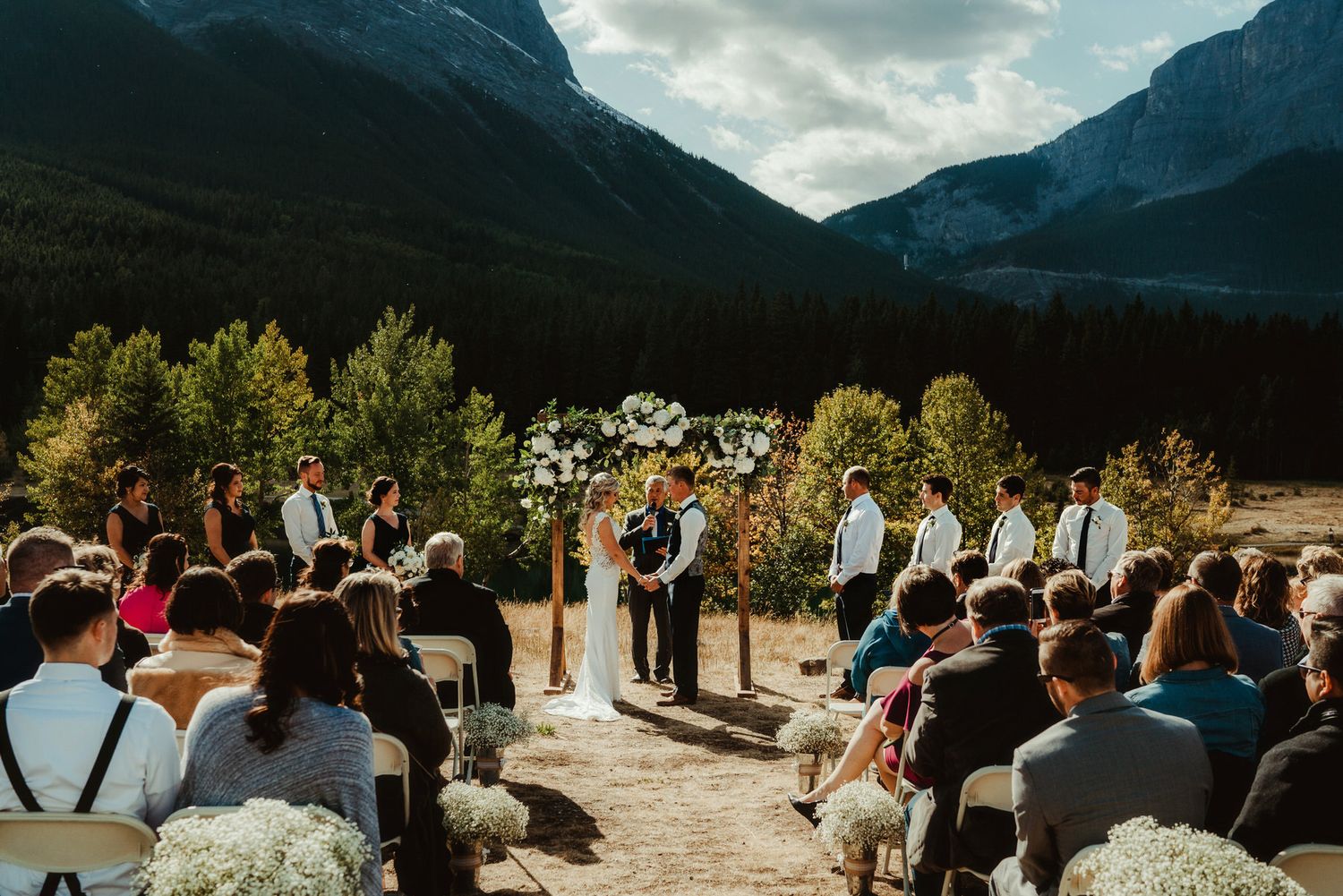 Wedding ceremony at Quarry Lake Park, featuring a couple under a floral arch, surrounded by lush greenery and guests enjoying the scenery.