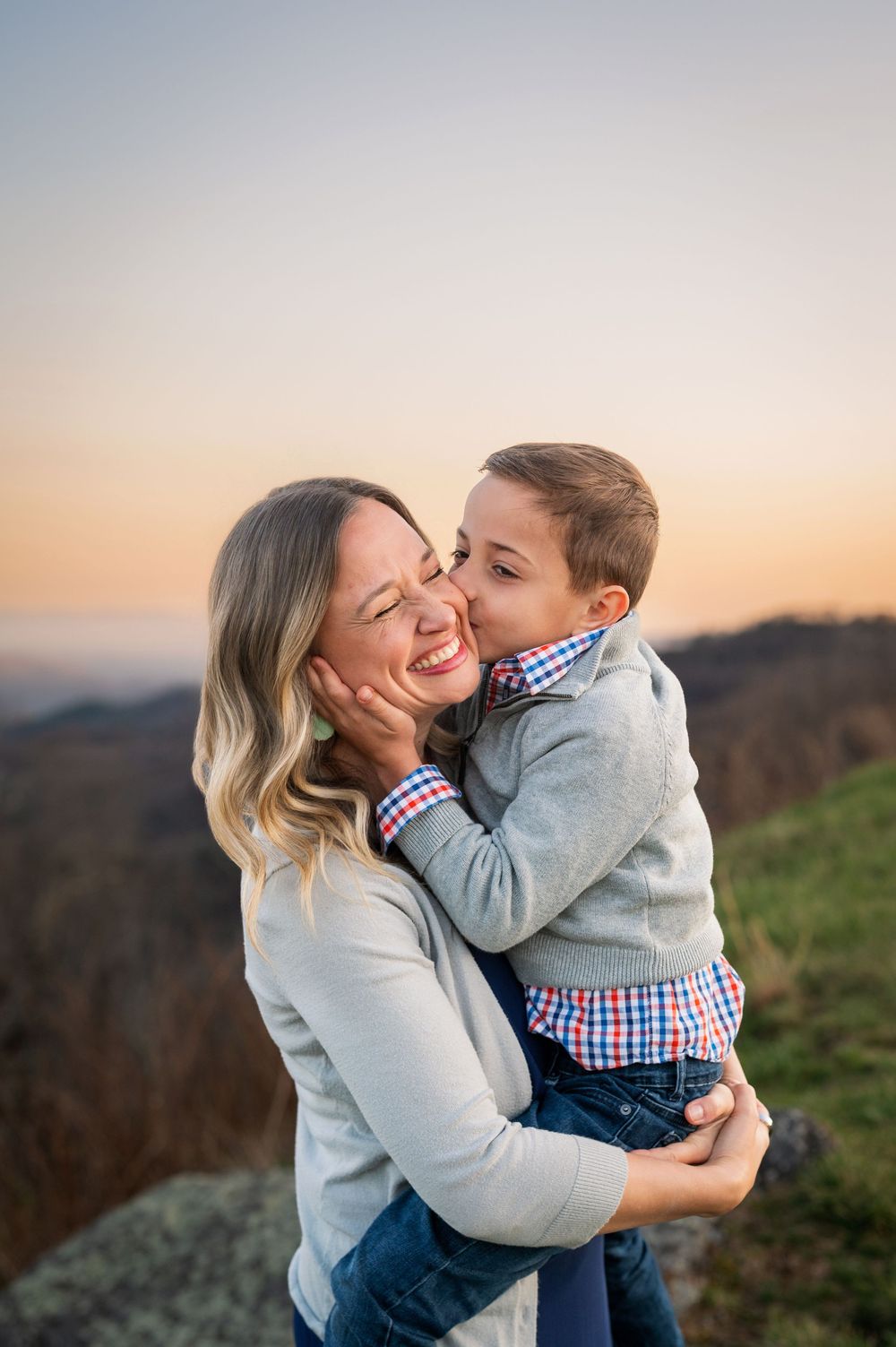Intimate moment between parent and child laughing together during sunset outdoors.