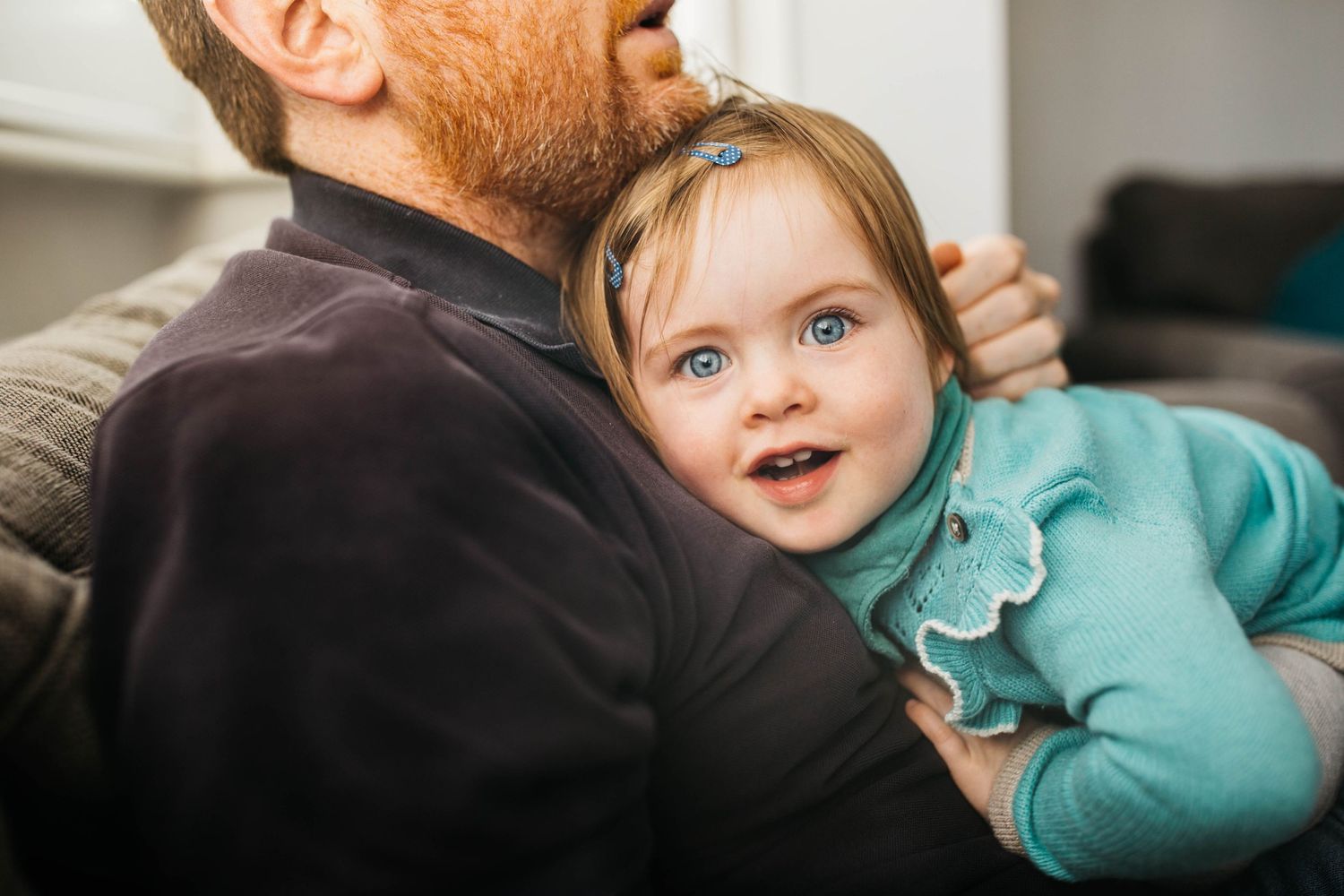 toddler girl cuddling daddy smiling at camera