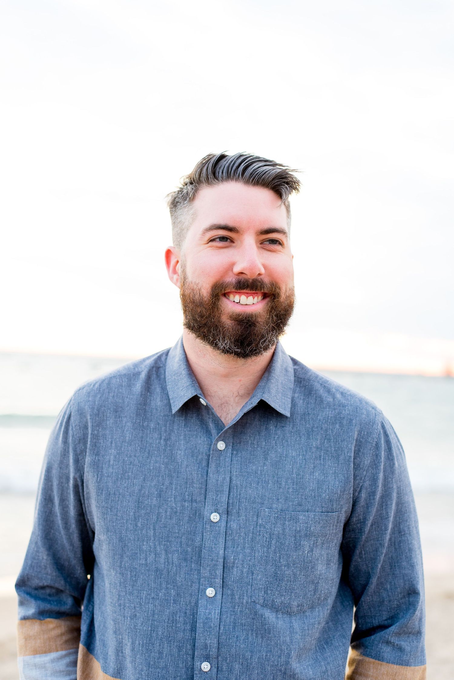 man with dark short hair and beard smiles on North Avenue Beach