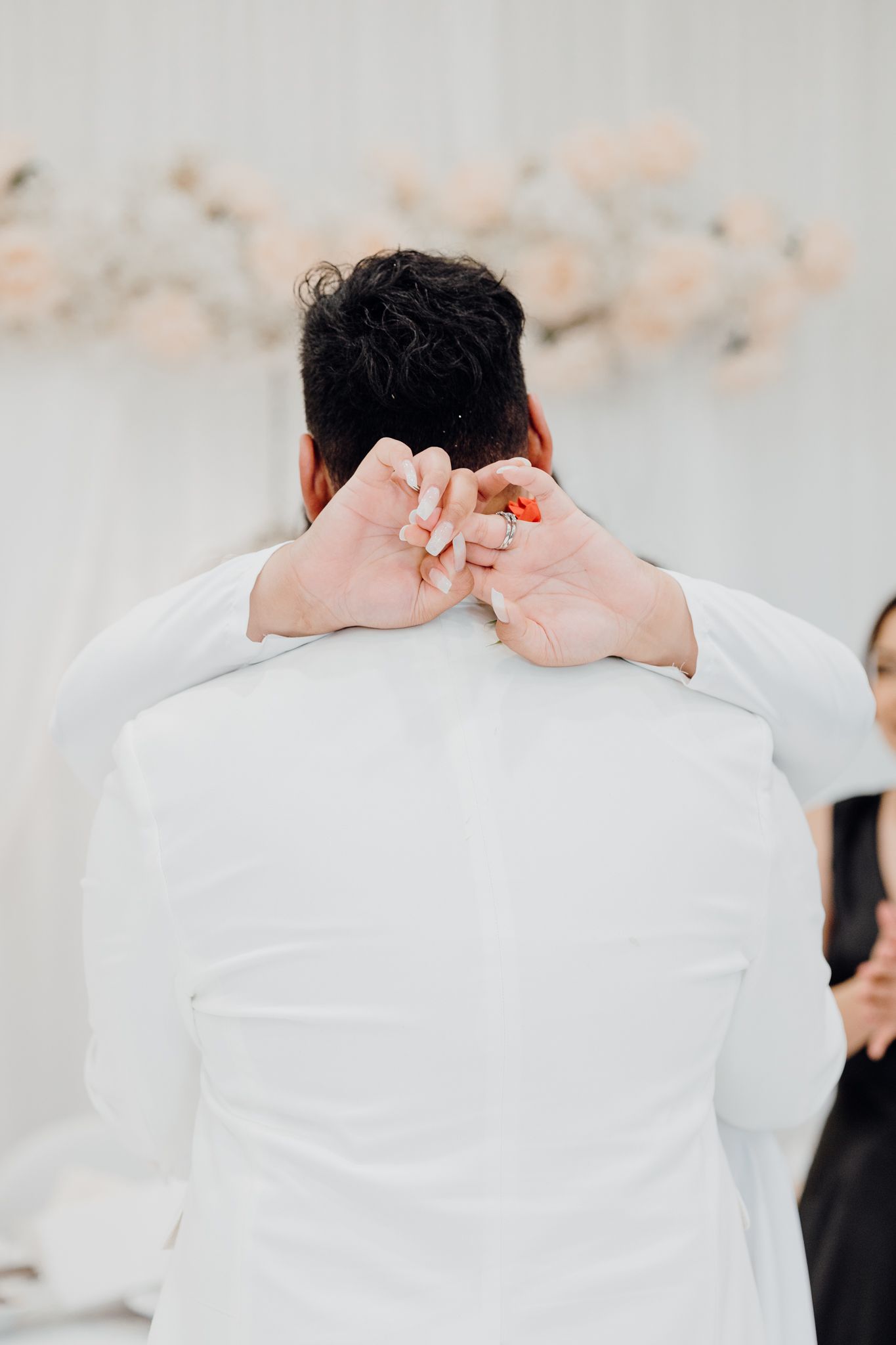 Back view of person in white suit jacket at formal event with floral decorations.