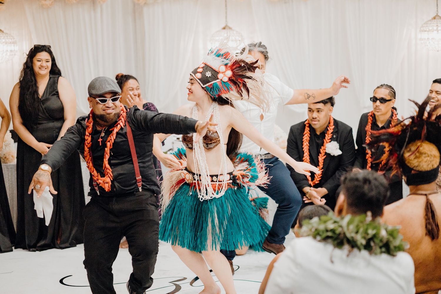 Traditional Polynesian dance performance with guests in formal attire at indoor wedding reception.