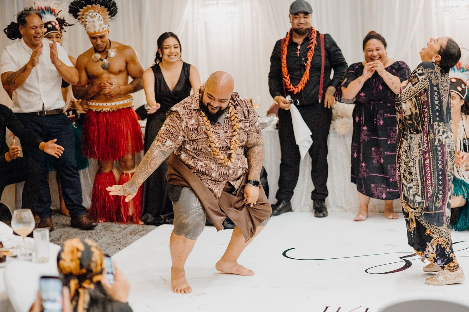 Traditional Hawaiian dancers perform during a wedding reception celebration on a white dance floor.