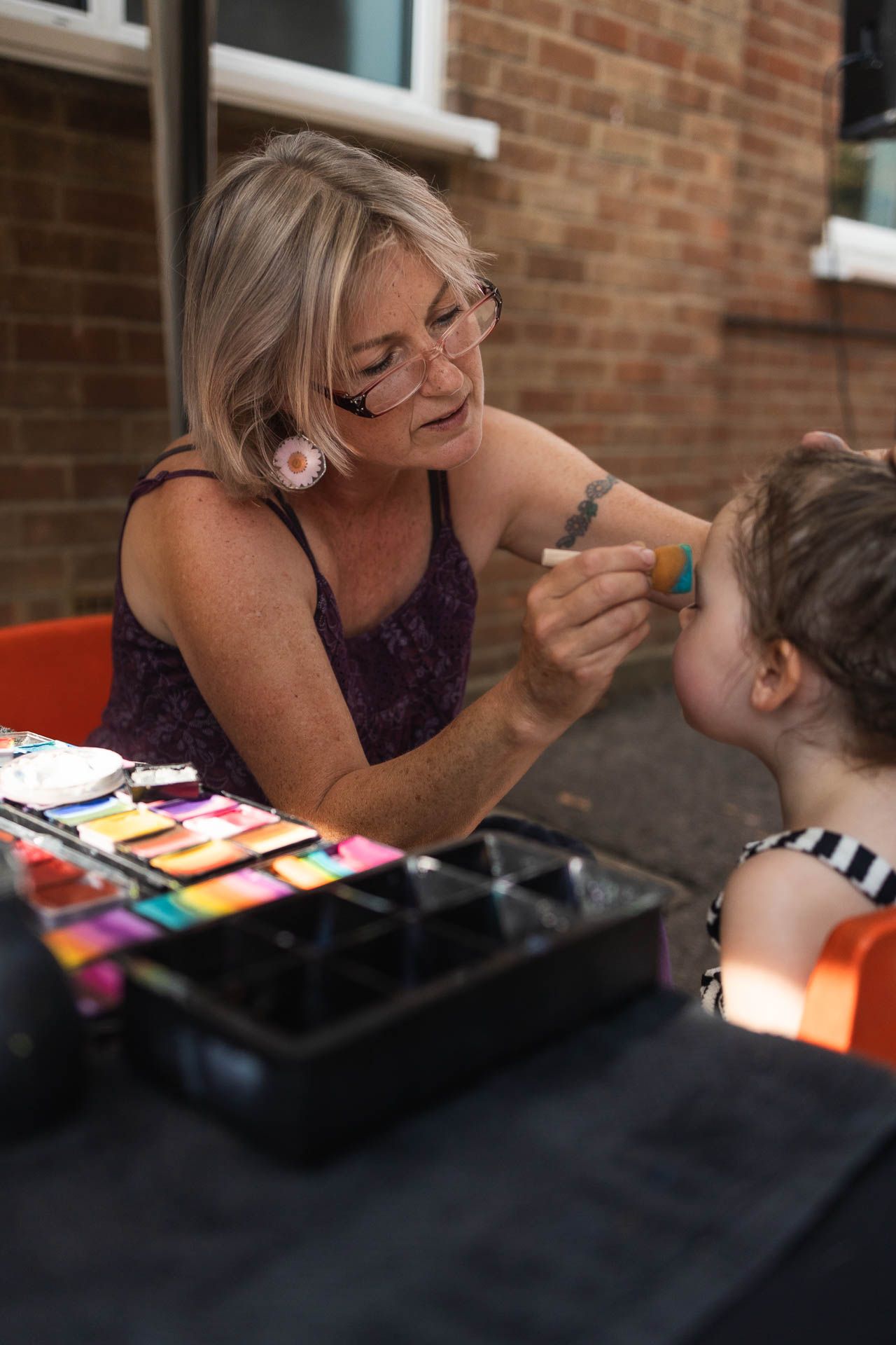 Face painter small business owner in action at summer fair, in Barnet, London.