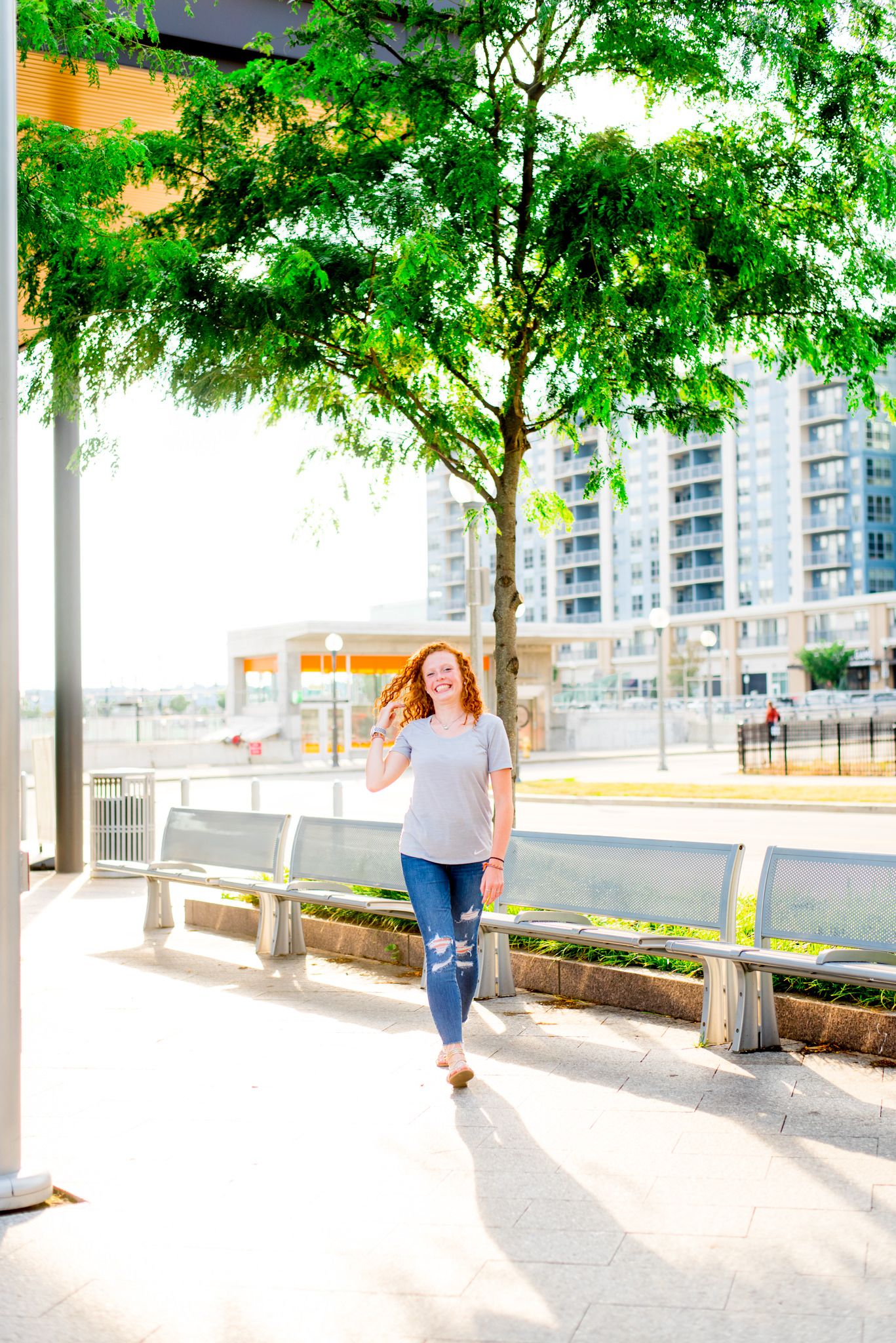 redhead girl in jeans and and grey shirt walking by tree at Smale Riverfront Park Downtown Cincinnati