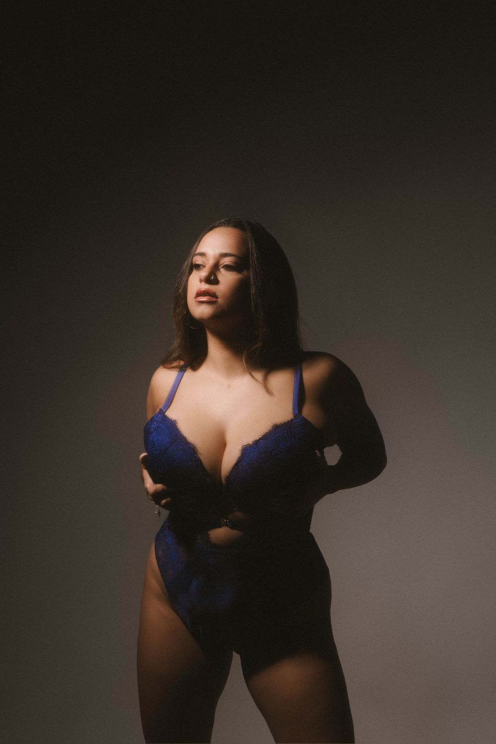 Studio portrait featuring navy blue lingerie against dark dramatic background.