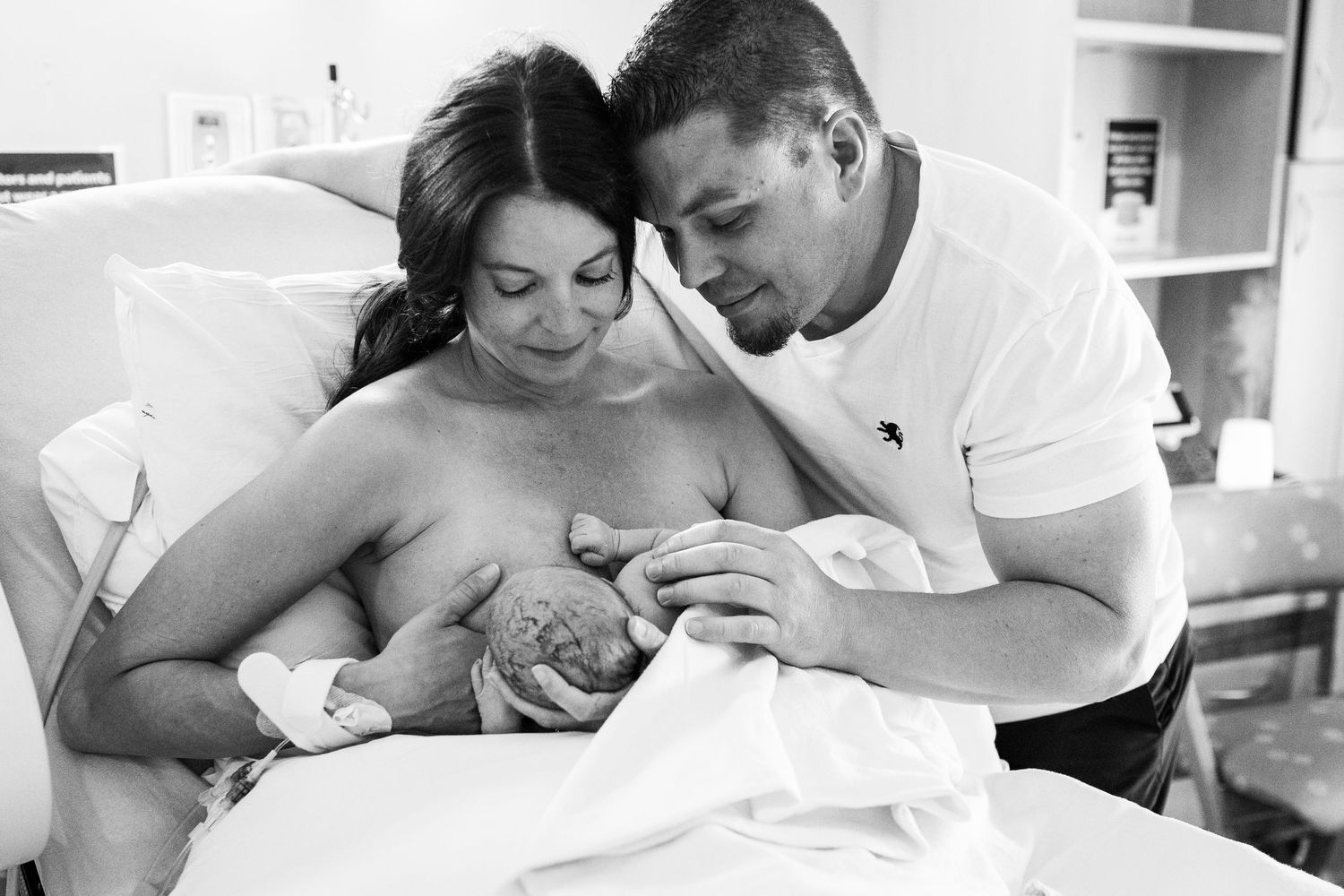A mother nurses her just-born baby as Dad looks on and cradles them both lovingly moments after birth in Lafayette CO
