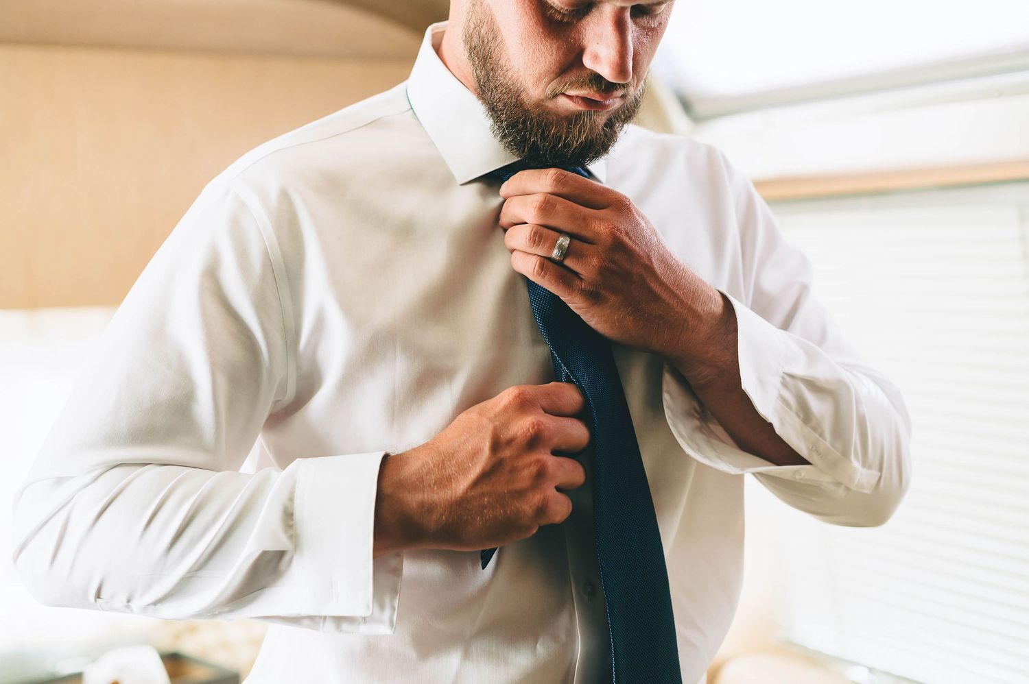 groom straightening his tie that matches the fabric of his kilt