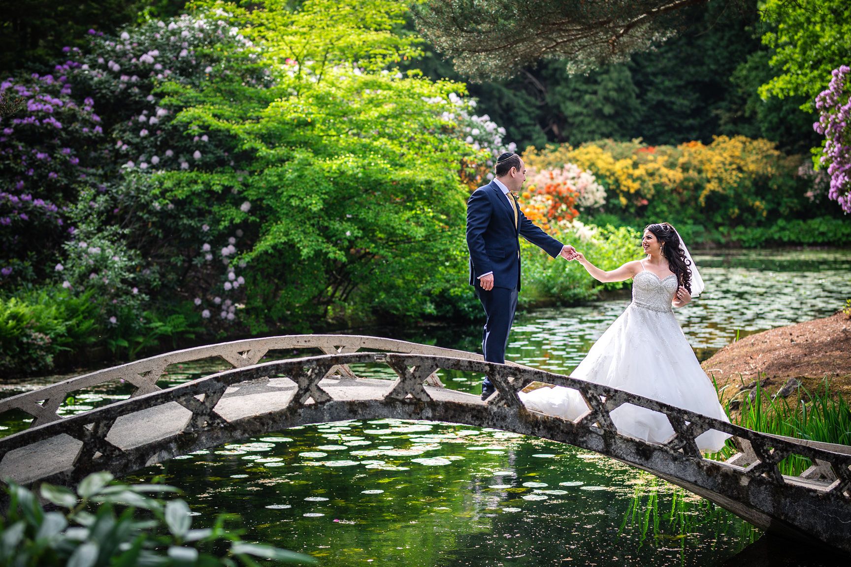 Manchester Jewish wedding photographer captures the bride and groom on a bridge at their Tatton Park wedding in Summer
