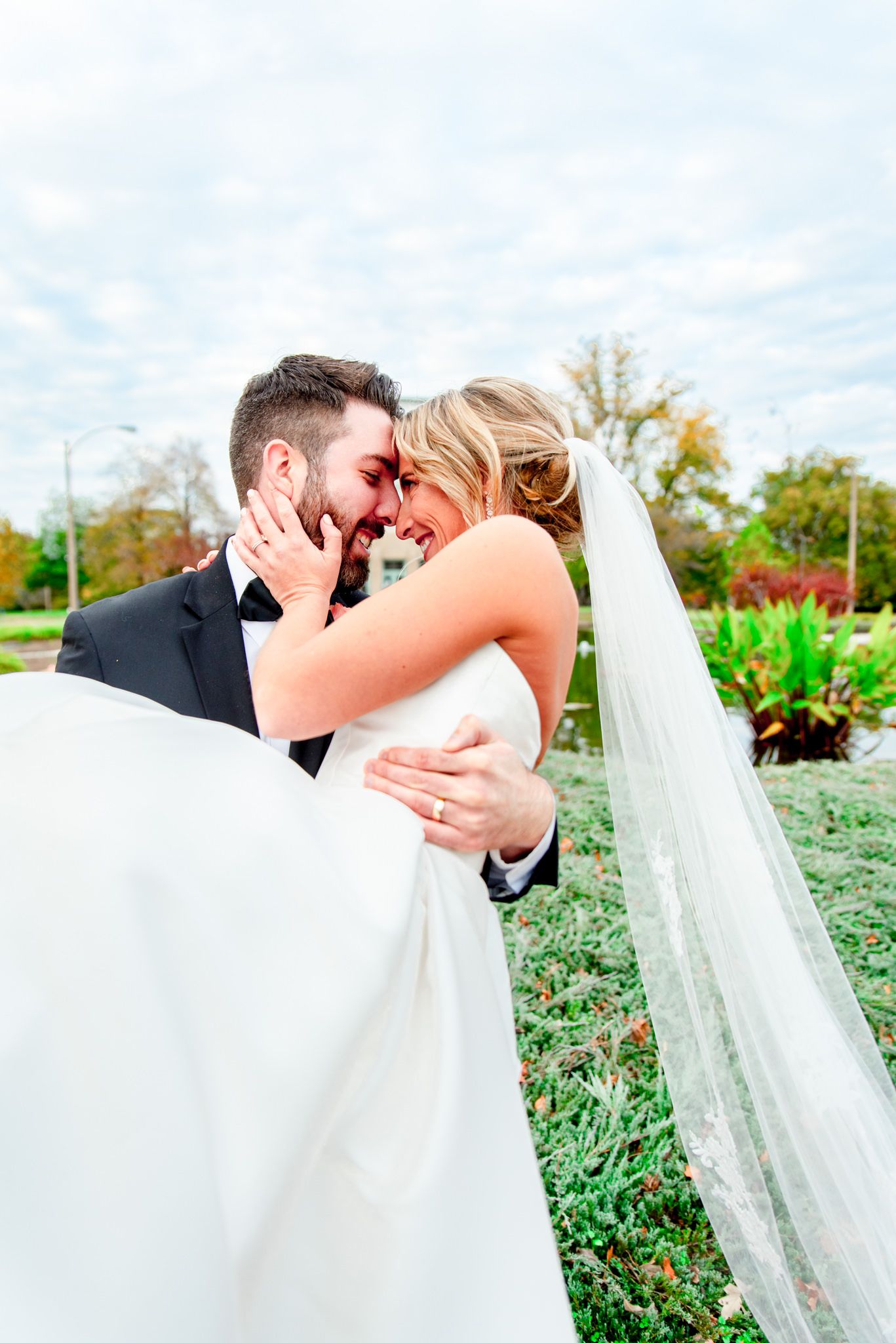 groom carrying bride in his arms and smiling at each other at the Jewel Box in Forest Park, STL