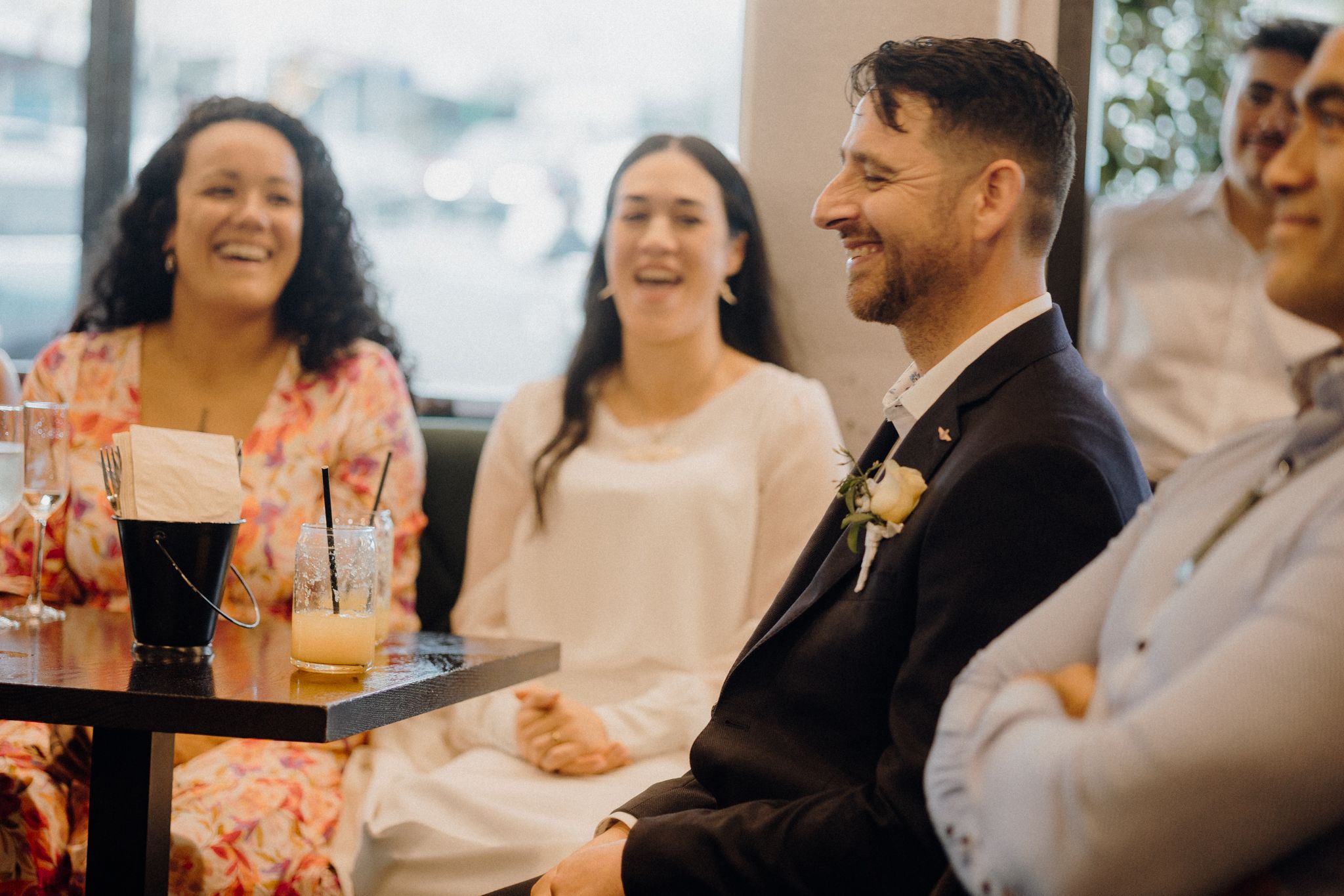 Wedding guests share drinks and laughter during a casual reception moment at a modern venue.