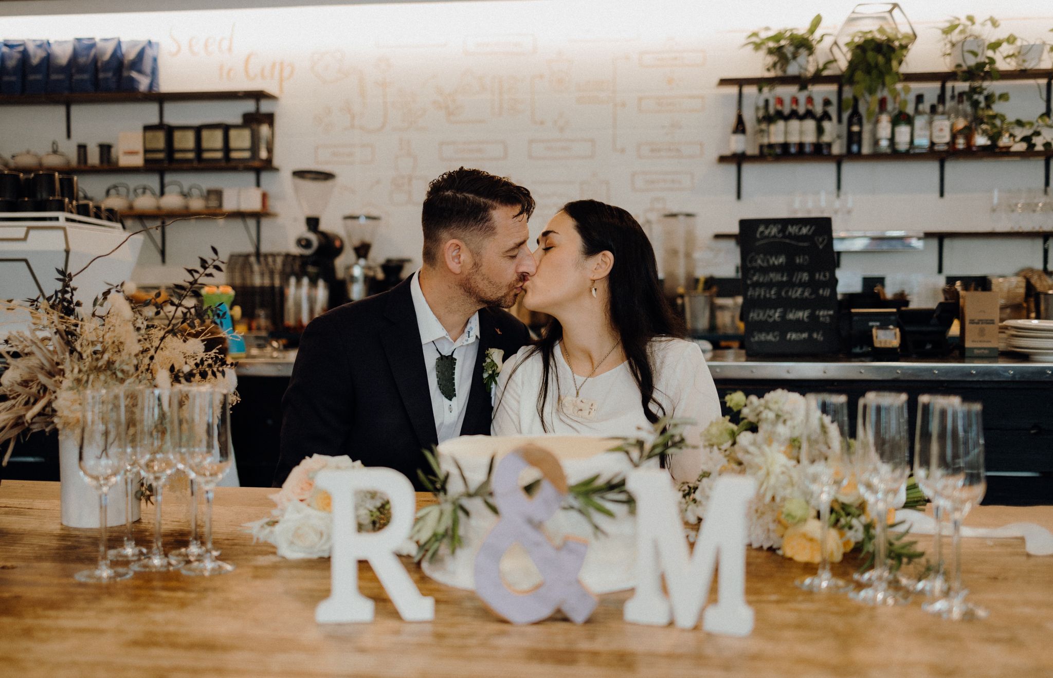 A romantic moment shared between newlyweds at their reception with decorative R&M letters.