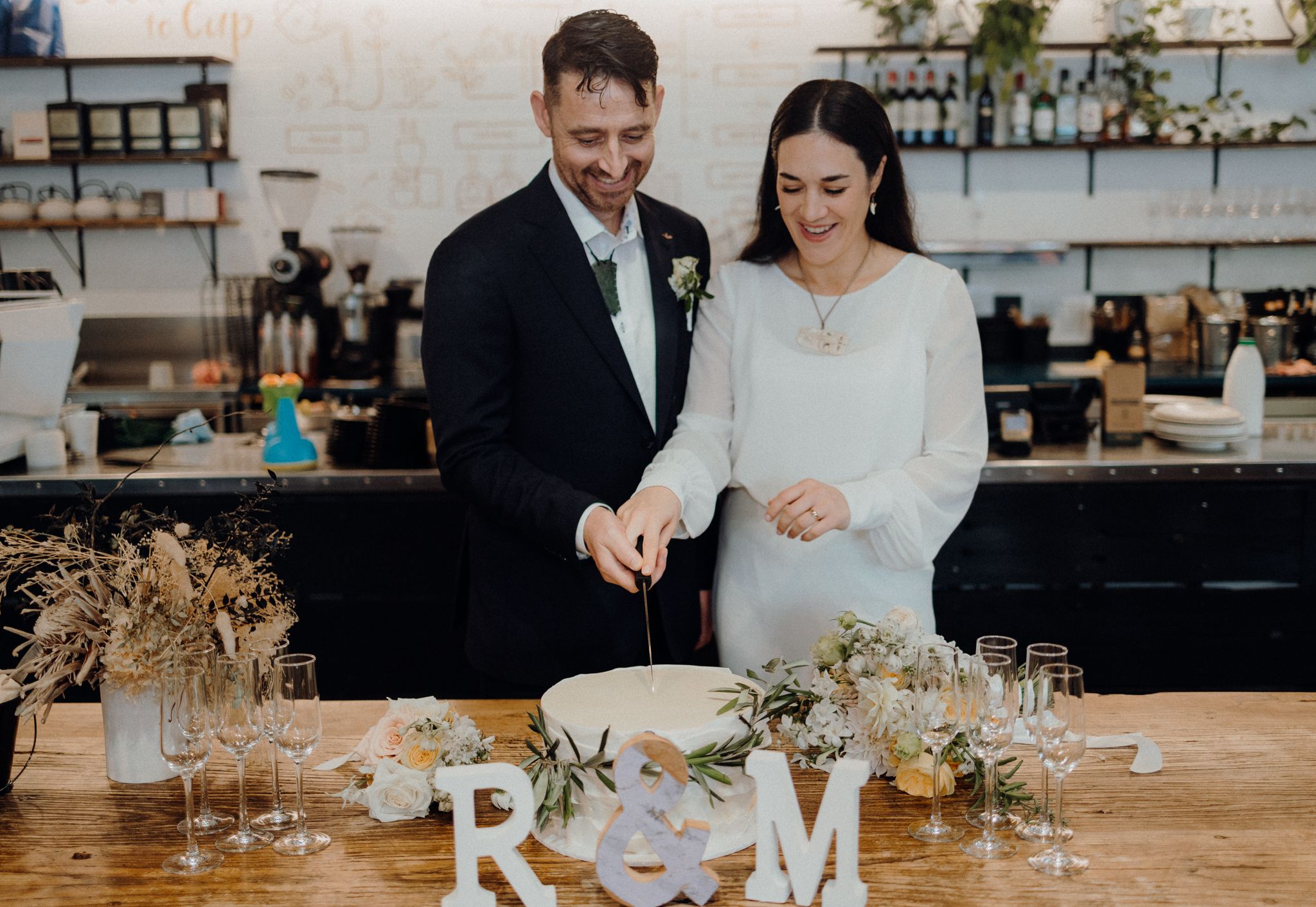 Couple cuts their wedding cake together at modern reception with R&M decor.