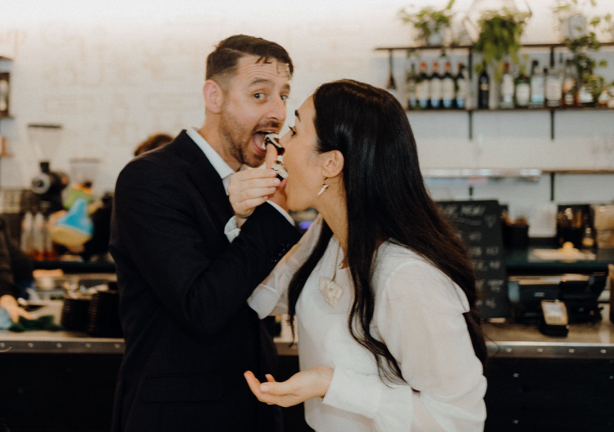 Newlyweds share a playful cake-feeding moment at their wedding reception.